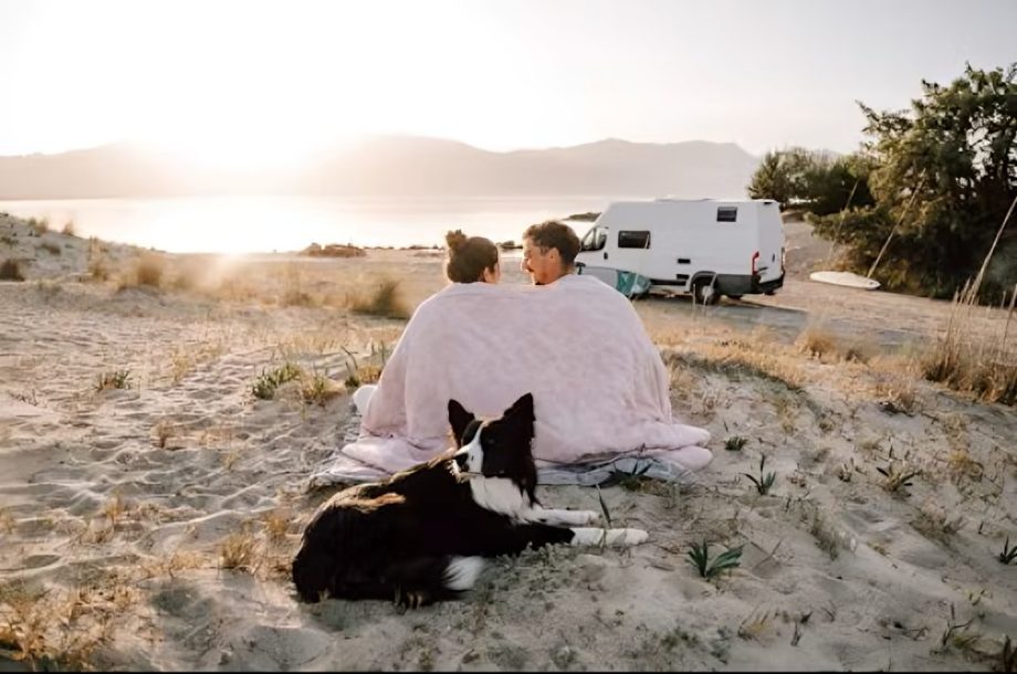 Couple wrapped in blanket on beach with dog