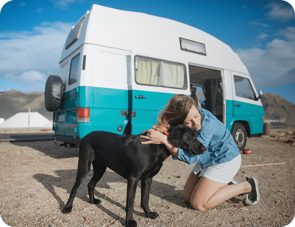 Woman hugging black dog by teal campervan